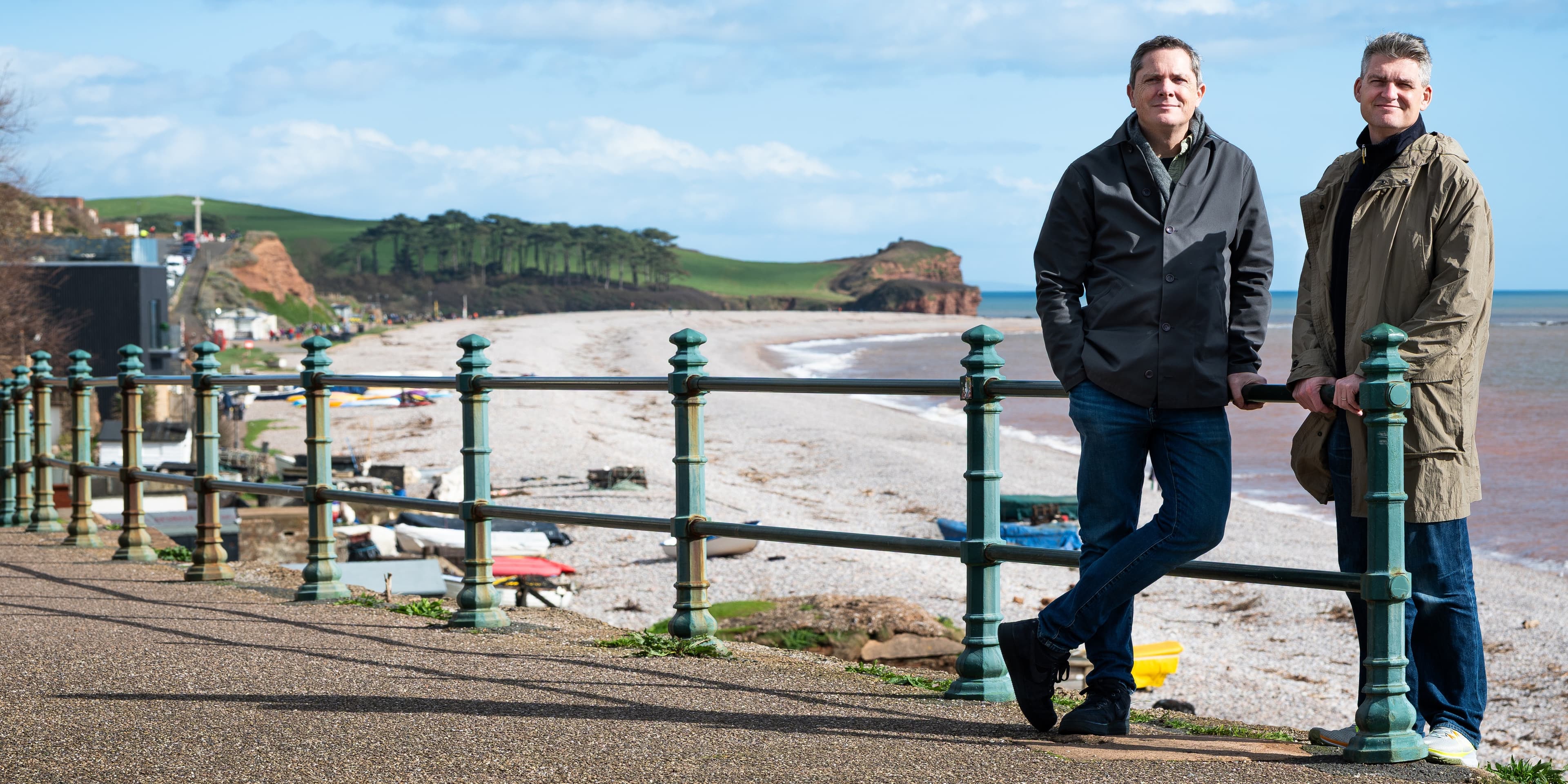 Two men standing on beach promenade overlooking coastal landscape